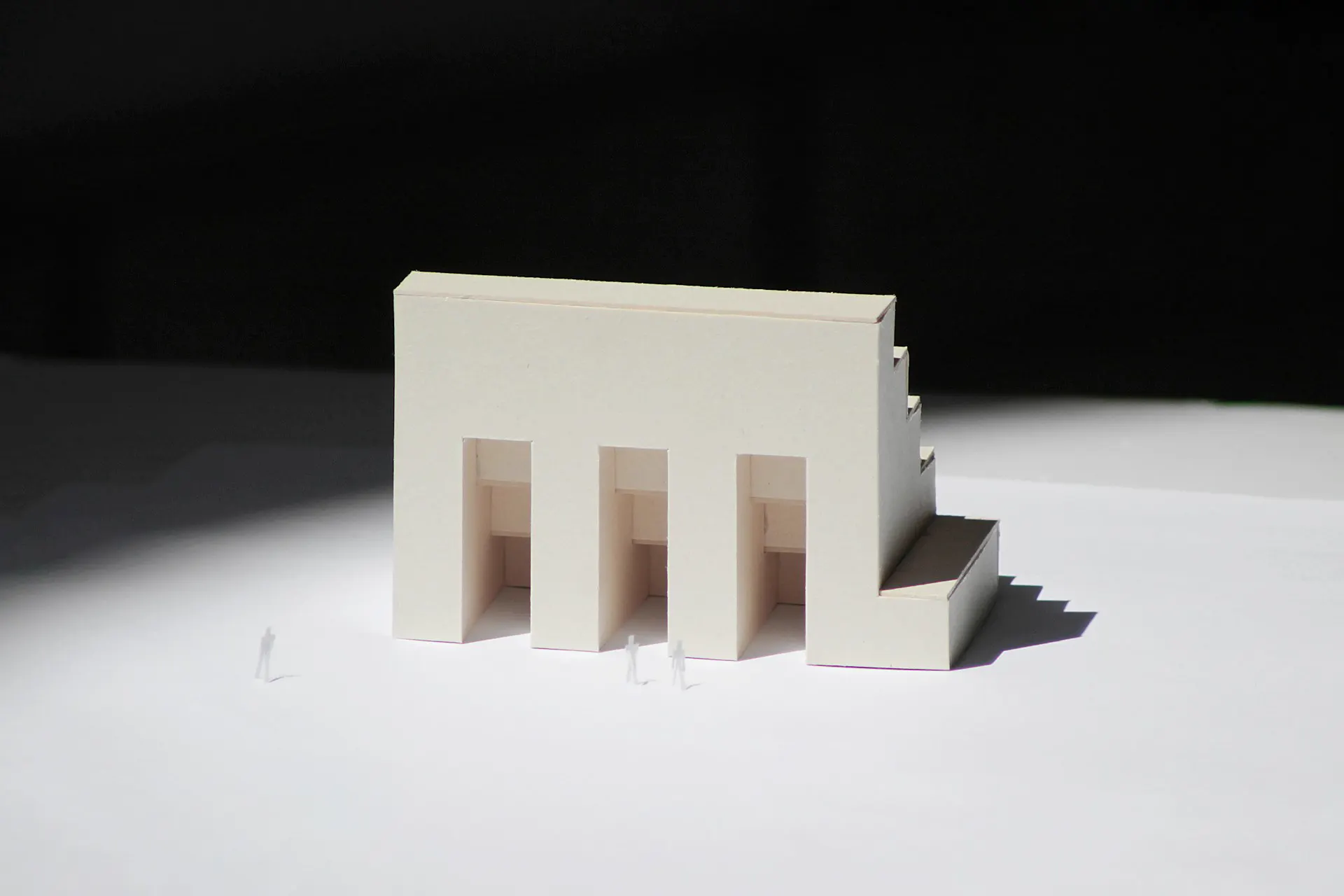 A white card model of a building with three arched openings