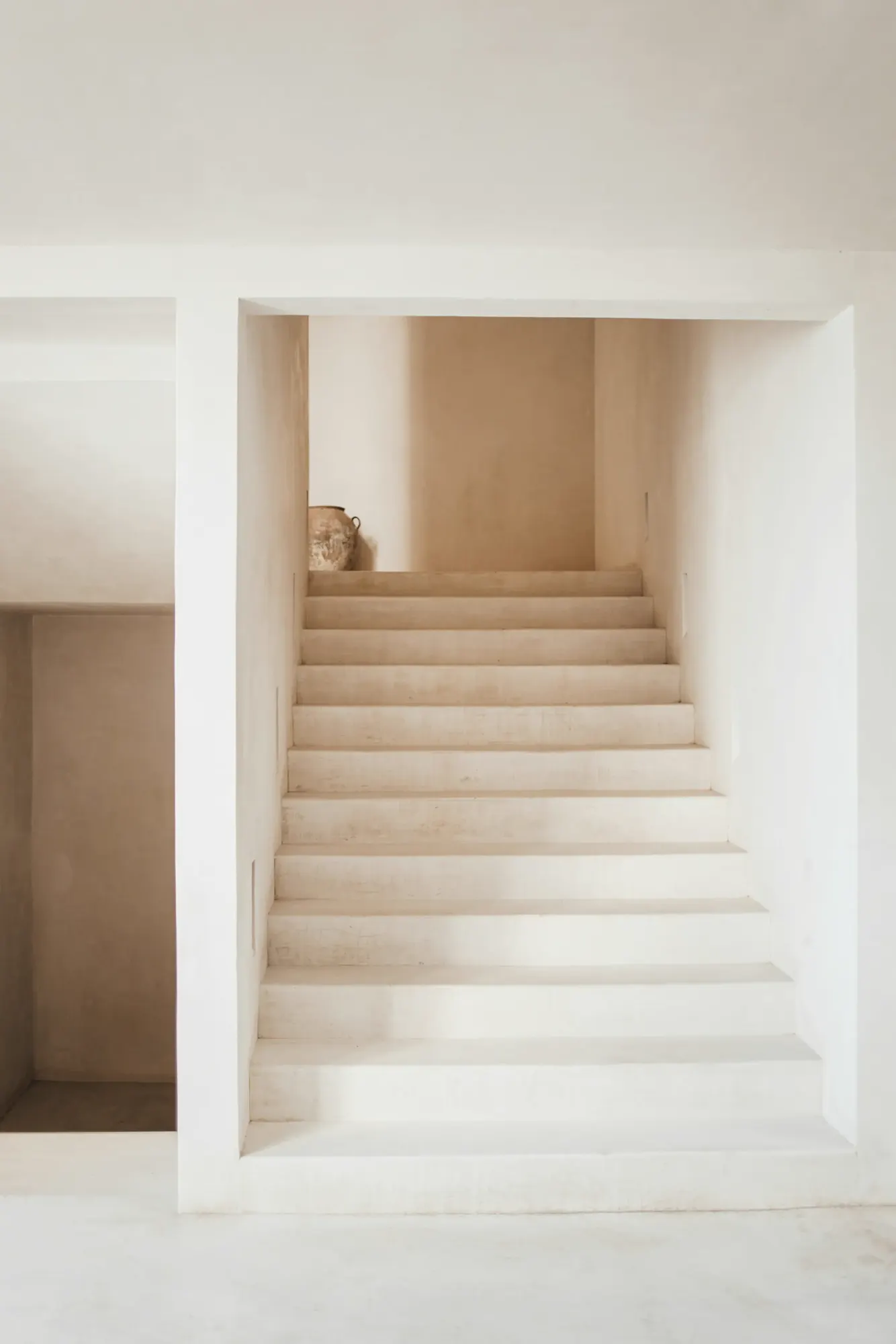 A pale staircase between smooth white walls